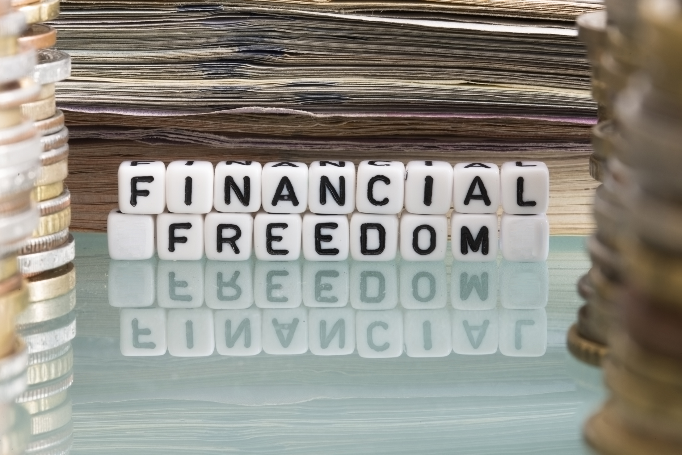 Financial freedom text from plastic beads between stack of cash money